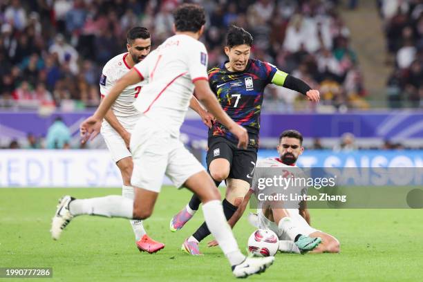 Son Heung Min of South Korea is challenged by Sadegh Moharrami and Mohammad Mohebi of Jordan during the AFC Asian Cup semi final match between Jordan...