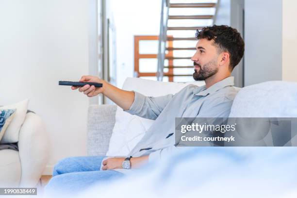 man watching tv on the sofa during the day. - cable tv stock pictures, royalty-free photos & images