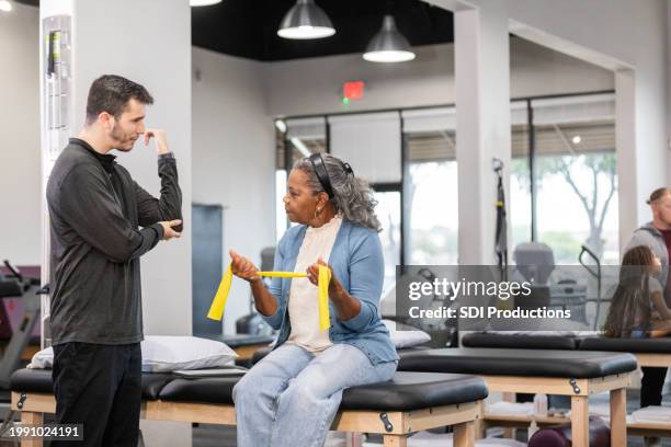 male occupational therapist demonstrates while he talks with his patient - rehabilitation center stock pictures, royalty-free photos & images