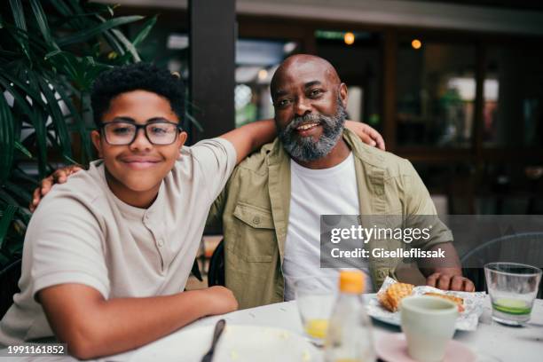 portraits of dad and son, having a meal in a restaurant - fathers day dinner stock pictures, royalty-free photos & images