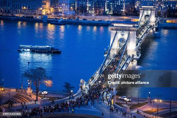 Dpatop - 09 February 2024, Hungary, Budapest: People demonstrate on the Chain Bridge after Hungarian President Novak pardoned a man in a case of...