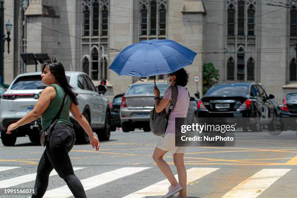 Pedestrians are protecting themselves from the intense heat in the central region of Sao Paulo, Brazil, on February 9, 2024.