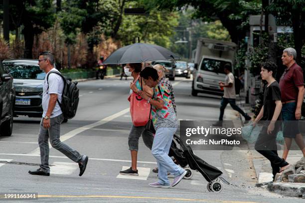 Pedestrians are protecting themselves from the intense heat in the central region of Sao Paulo, Brazil, on February 9, 2024.