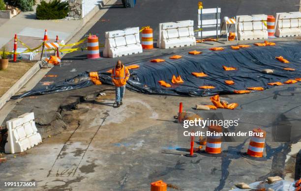 Rancho Palos Verdes, CA A construction worker walks along cracked pavement where land movement exacerbated by recent storms has caused large cracks...