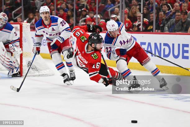 Jason Dickinson of the Chicago Blackhawks is upended by Adam Fox of the New York Rangers while battling for control of the puck in overtime on...