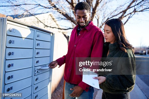 Young Mixed-Race Couple Hispanic and African American in Their Twenties Placing Mail-In Ballots Into a Neighborhood Mail Box