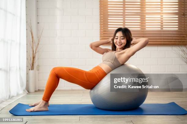 asian young beautiful sportswoman doing yoga pilates workout at home. attractive girl in sportswear practice exercise pose breathing and meditation with yoga ball for health care in fitness studio. - yoga ball work 個照片及圖片檔