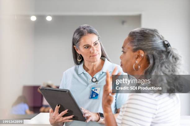 mature female patient gestures while asking the physical therapist questions - cuidados de saúde primários imagens e fotografias de stock