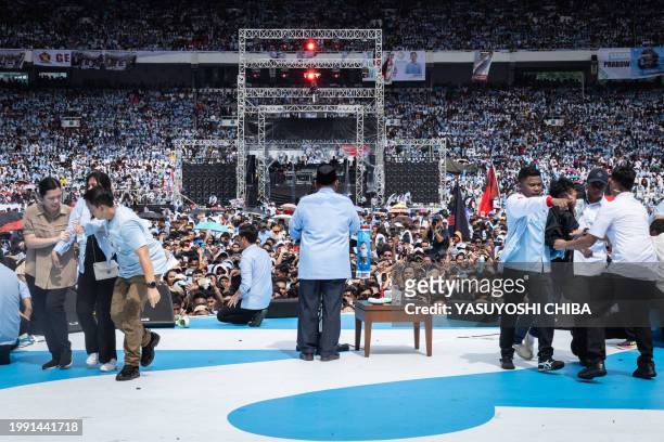 Presidential candidate and Indonesia's Defence Minister Prabowo Subianto delivers a speech as people are helped onto the stage amid the mass of...