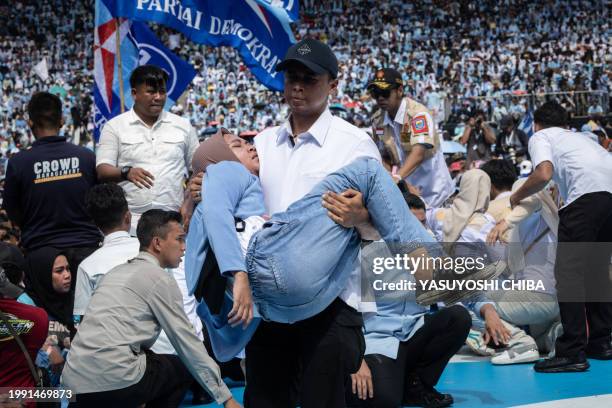 Woman is carried on the stage after being removed from the crowd amid the mass of supporters during a campaign rally by presidential candidate and...