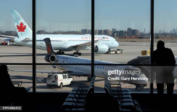 Person watches an Air Canada airplane being towed away from a gate at Terminal 1 at Pearson International Airport on February 6 in Toronto, Canada.