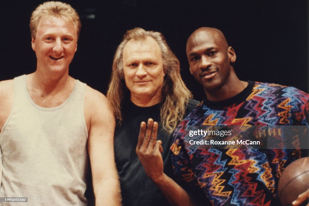 Michael Jordan holds up three fingers and holds a basketball with
