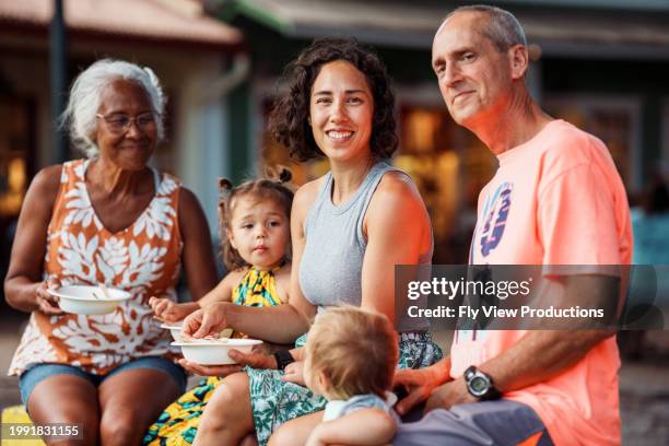 mehrgenerationenfamilie sitzt draußen und isst hawaiianisches shaved ice - hawaiianischer-abstammung stock-fotos und bilder