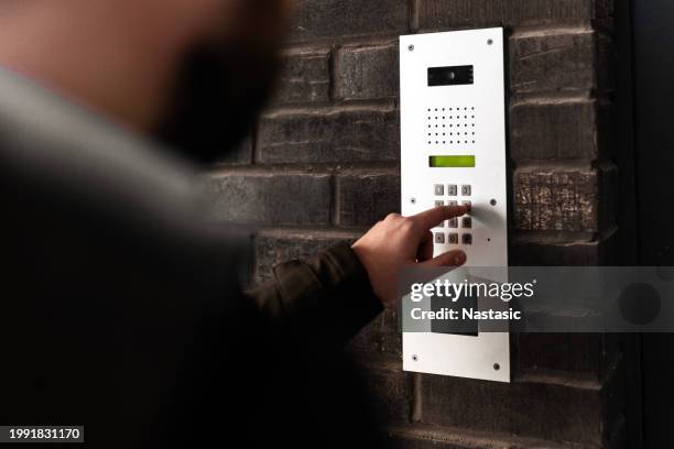 young man dialing apartment entry - bell telephone company stock pictures, royalty-free photos & images