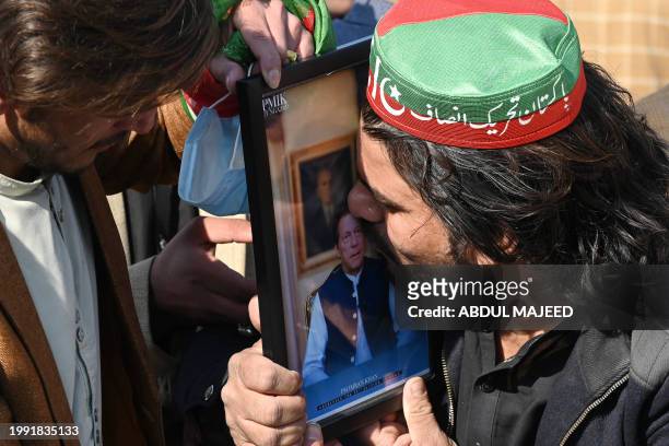 Supporter of the Pakistan Tehreek-e-Insaf kisses a portrait of jailed former prime minister and party leader Imran Khan during a protest outside a...