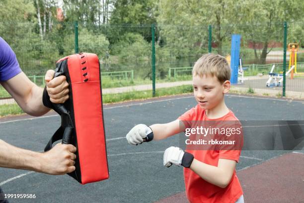outdoor martial arts training - boy in sports gloves perfecting strikes - boxing gloves stock pictures, royalty-free photos & images