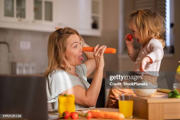 funny mother and daughter having fun whit vegetables in the kitchen - dranken en maaltijden stockfoto's en -beelden