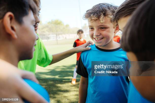 youth soccer team enjoying a group huddle on the field - tweenies stockfoto's en -beelden