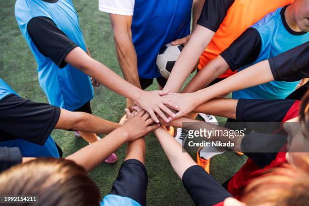 youth soccer team united hands on football before game - club football stock pictures, royalty-free photos & images