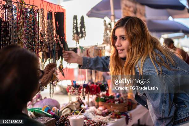junge kundin kauft accessoires und spricht mit verkäufer im accessoires-geschäft - marktplatz stock-fotos und bilder