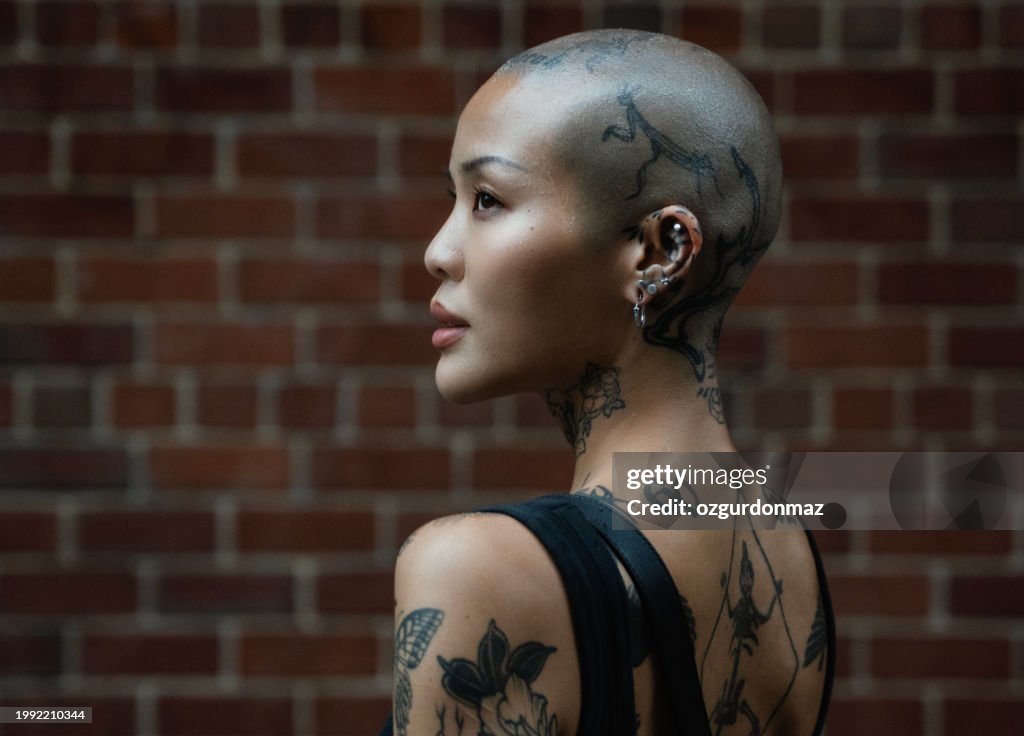 Street portrait of a young, beautiful bald woman with many tattoos