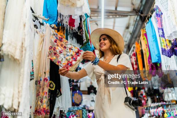 giovane donna che cerca vestiti al mercato - negozio di souvenir foto e immagini stock