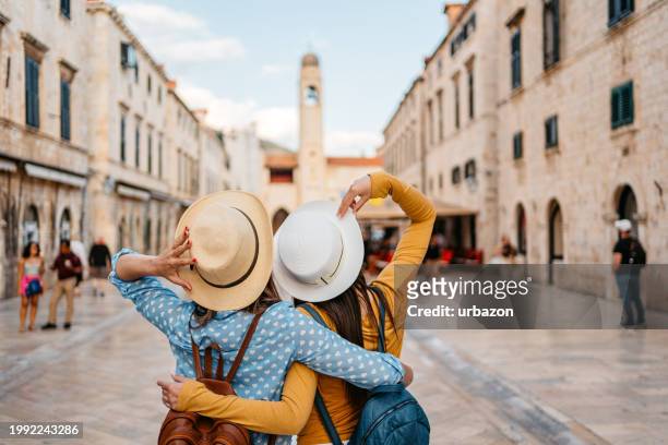 two young female friends embracing on the street in dubrovnik - old town stock pictures, royalty-free photos & images