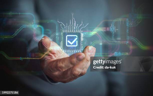 digital agreement technology in your hand. male hand holding futuristic check mark icon in the center and circuit board with vibrant data transfers, representing evolving assistance technology of the future. - control center stockfoto's en -beelden