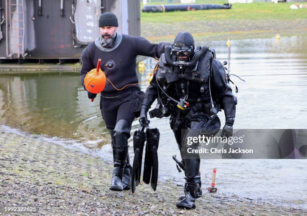 Specialist underwater explosive ordinance disposal operators for the Royal Navy walk out of the water after a demonstration during her visit by...