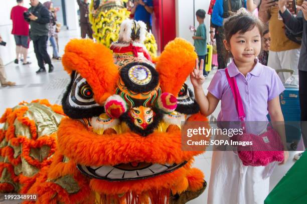 Kid poses for a photo next to a dancer dressed in a lion costume during Chinese New Year celebration at Padalarang High Speed Train Station in...