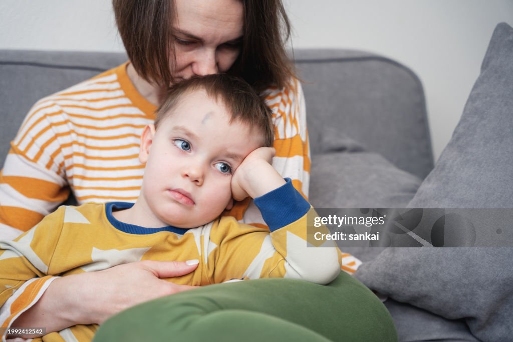Loving mother comforting son with bruise on the forehead