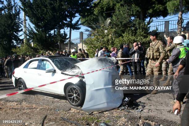 Blood stains cover the ground next to a a car wrecked in a reported Israeli drone attack, as Lebanese army soldiers secure the area in the village of...