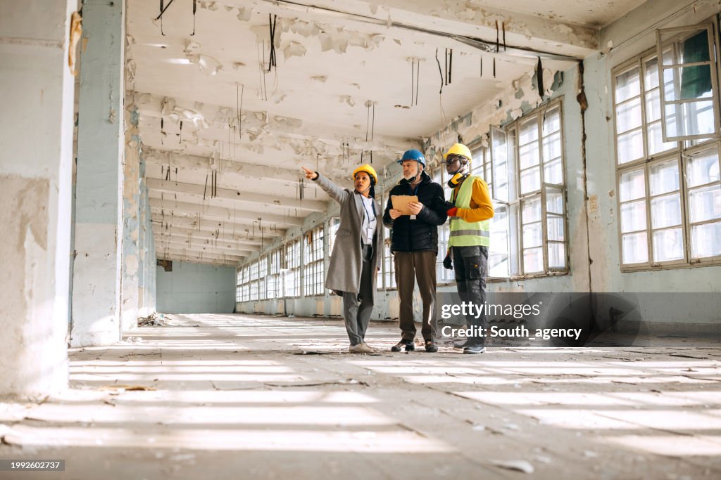 Architects looking at the architectural project and explaining to construction worker what to do