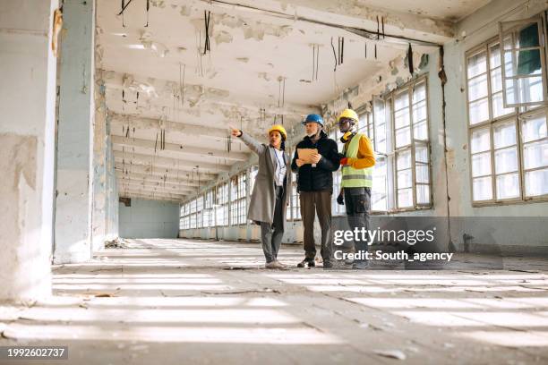 architects looking at the architectural project and explaining to construction worker what to do - byggnadskonstruktion bildbanksfoton och bilder