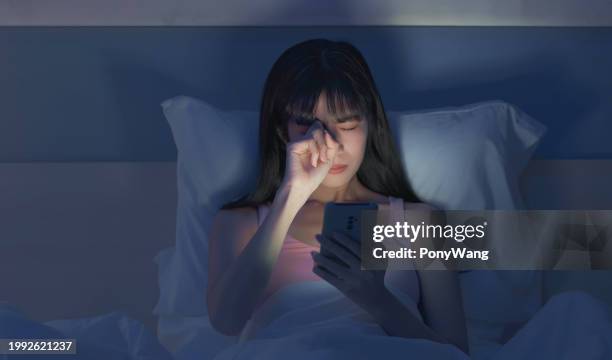 asian woman scroll smartphone dark - conjunctivitis stock pictures, royalty-free photos & images