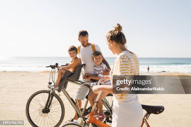 young family riding bicycles in summertime - beach bike stock pictures, royalty-free photos & images