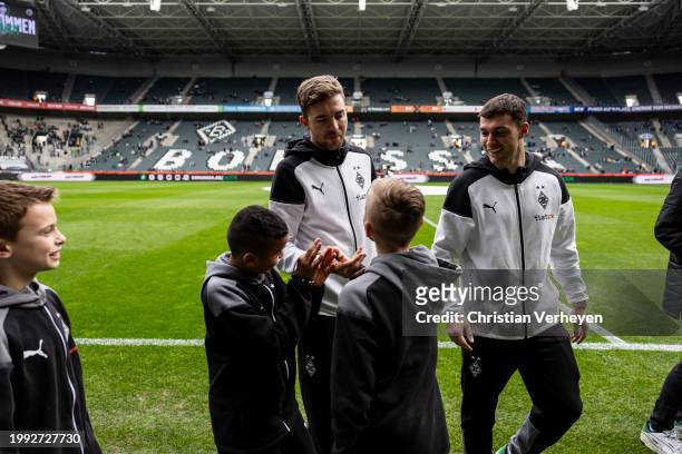 Christoph Kramer and Joe Scally of Borussia Moenchengladbach are seen with some kids ahead of the Bundesliga match between Borussia Moenchengladbach...