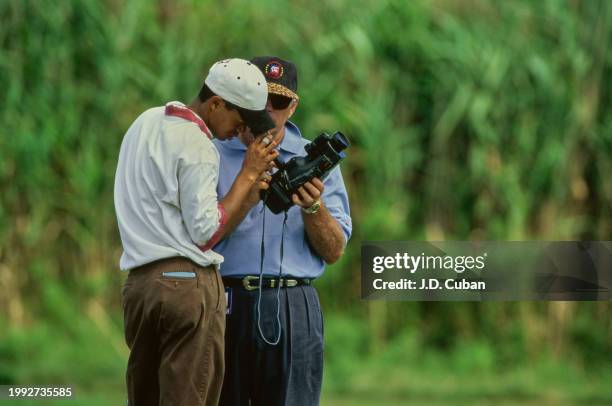 Tiger Woods from the United States in conversation with golf coach Butch Harmon reviewing his golf swing on a hand held video camera during practice...