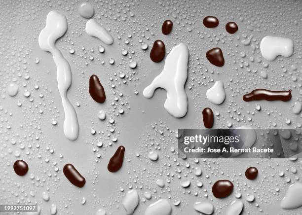 drops of hot liquid chocolate and milk on a surface with small drops of water. - chocolate milk splash stock pictures, royalty-free photos & images