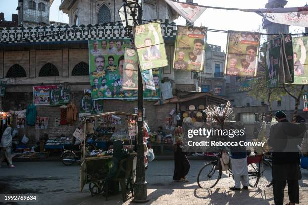 Pakistani residents walk past flags depicting candidates from different political parties ahead of the forthcoming general election on February 07,...