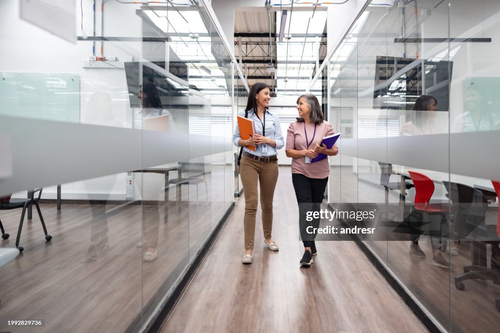 Happy female teachers talking in the hall at the university