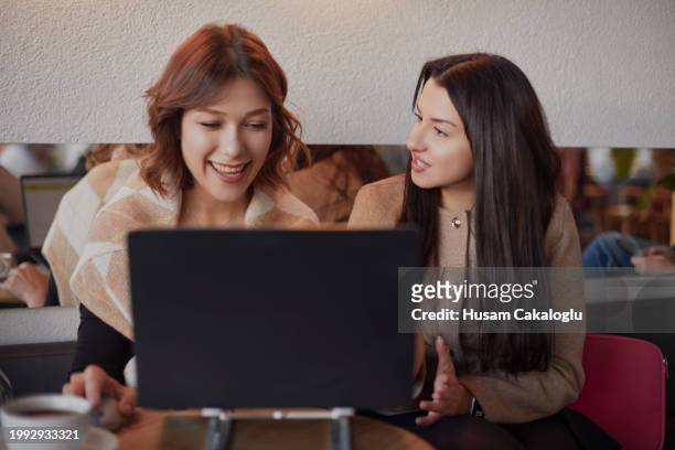 two close friends are working with a computer together in a café. - narrar fotografías e imágenes de stock