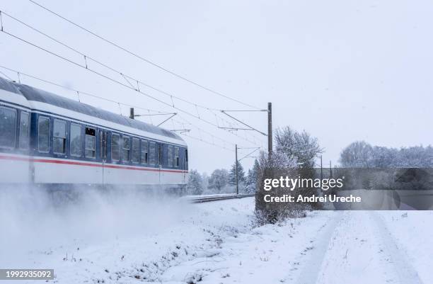 passenger train passing through snowy fields in germany - stuttgart village stock pictures, royalty-free photos & images