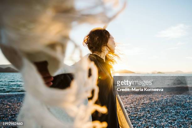 calm woman with flying scarf in the wind on the beach. - woman flying scarf stock pictures, royalty-free photos & images