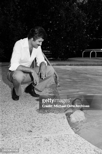 Greek-born American actor John Aniston poolside with his daughter, American actress Jennifer Aniston, in the swimming pool at the family home in the...