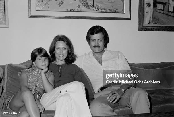 American actress Jennifer Aniston with her mother, American actress Nancy Dow and father, Greek-born American actor John Aniston, sitting on a sofa...