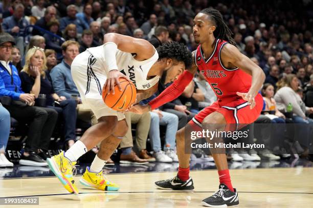 Dayvion McKnight of the Xavier Musketeers tres to get by Daniss Jenkins of the St. John's Red Storm during a college basketball game at the Cintas...