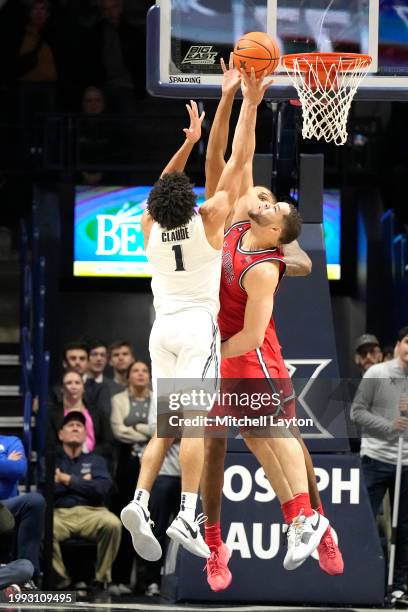 Desmond Claude of the Xavier Musketeers takes a shot over Chris Ledlum of the St. John's Red Storm during a college basketball game at the Cintas...