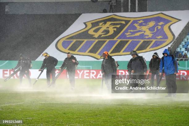 Grounds staff use leaf blowers to clear water from the surface of the pitch prior to the DFB cup Quarterfinal match between 1. FC Saarbrücken and...