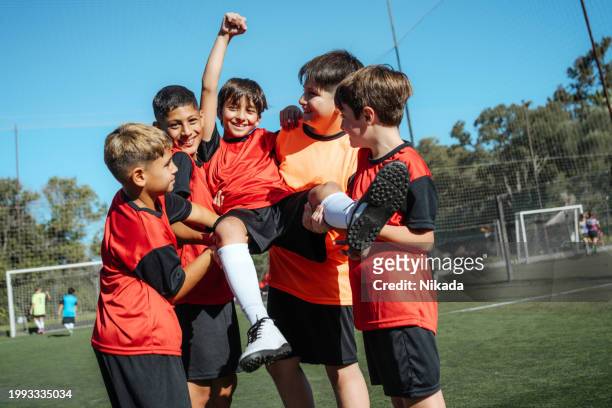 de jeunes joueurs de football joyeux célèbrent la victoire sur un terrain ensoleillé - sport and team photos et images de collection